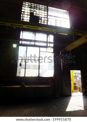 ray of sunlight entering through the open door of an industrial hall and brightness in a dirty window