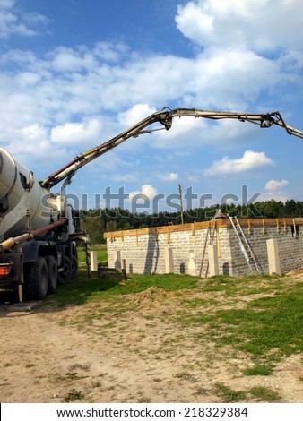 concrete mixer truck with pump on the site is preparing to pour concrete on the roof of a small house