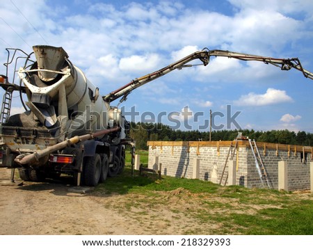 concrete mixer truck with pump on the site is preparing to pour concrete on the roof of a small house