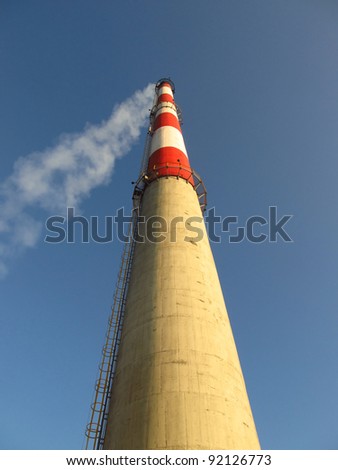 high white-red chimney against a blue cloudless sky