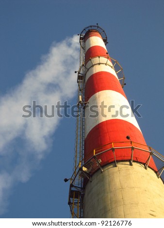 high white-red chimney against a blue cloudless sky