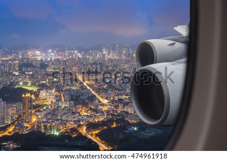 Window seat on airplane overlooking Hong Kong night view . Jet engine on the wing , on fly .