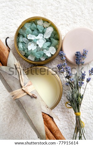 Spa composition with bath salt, moisturizer, round soap bar, lavender flowers and cinnamon sticks arranged on the towel. Top view