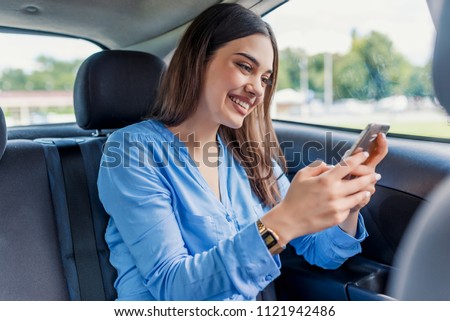 nice beautiful young woman smile and use mobile phone touching the screen inside the car while travel. modern concept of search hings and contact friends when you are away. daily use of smartphone