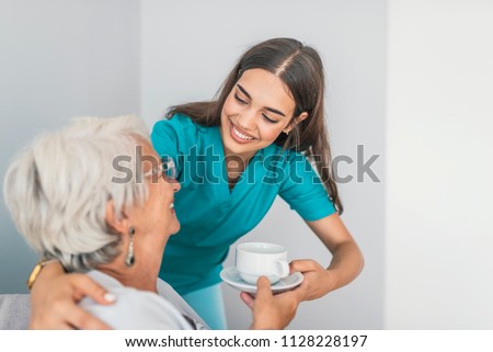 Pretty helpful carer talking with female patient. Health visitor and a senior woman during home visit. Supportive senior care assistant and smiling older woman in nursing home