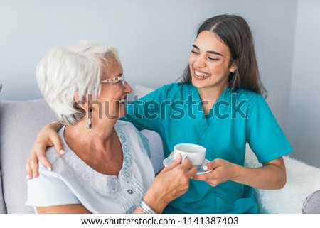 Happy senior woman talking with friendly nurse at geriatric ward. Helpful young pretty woman and lovely older lady. Professional helpful caregiver comforting smiling senior woman at nursing home