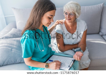 Home care nurse measuring blood pressure of senior woman. Medical care, insurance, prescription, paper work or career concept. Older person is having blood pressure checked