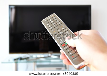 Remote control in the hand against TV screen