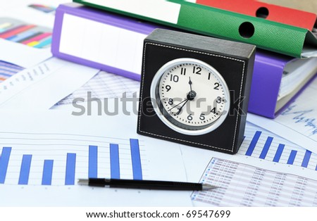 Clock, files and pen on a market report
