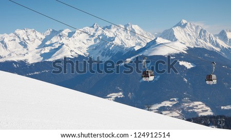 Gondola ski lift and snow covered mountain range in the background.