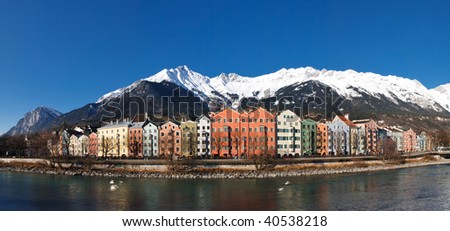 Innsbruck: Panoramic View of Colorful Houses at the Inn Riverside in Innsbruck, Austria. Clear blue sky. Snowy Mountains.