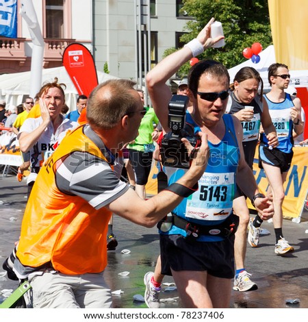 MAINZ, GERMANY - MAY 8: A unidentified photographer takes a photo of a runner cooling himself with a cup of water at the Gutenberg Marathon on May 8, 2011 in Mainz, Germany. 9,500 runners participate in the event.