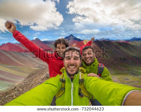 happy friends hikers takes photo selfie in Vinicunca, Peru with background of Rainbow Mountain (5200 m) in Andes, Cordillera de los Andes, Cusco region in South America with cloudy sky