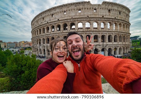 Young handsome couple at the Colosseum, Rome - Happy tourists visiting italian famous landmarks taking selfie photo