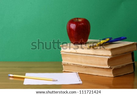 A chalkboard with an apple, a pencil and books