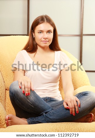 A young smiling woman sitting on the sofa at home