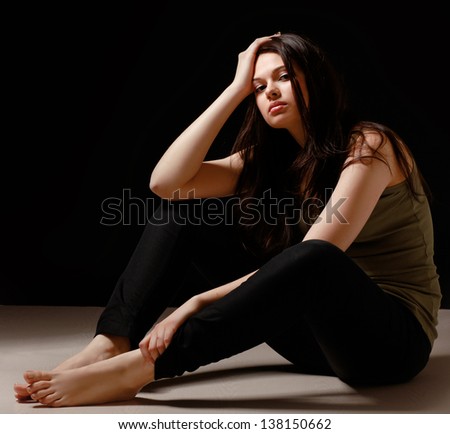 Depressed woman sitting on floor isolated on black background