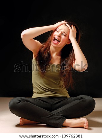 Depressed woman sitting on floor with eyes closed, isolated on black background