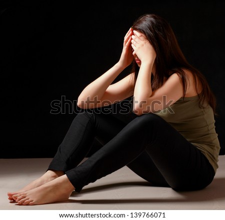 Depressed woman sitting on floor isolated on black background