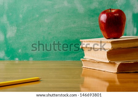 Stack of books with apple and  pencil . Isolated on green