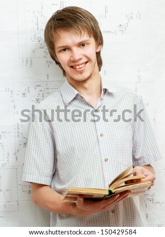 A young man near a diagram, holding a book