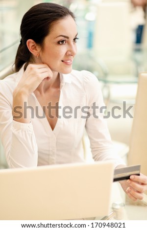 Happy woman sitting on the desk and shopping online
