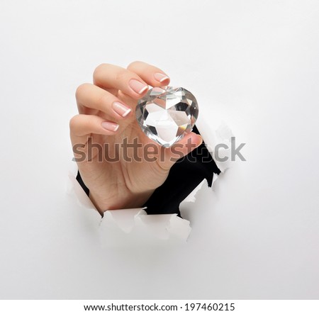 female hand with a diamond, tearing white paper