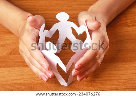 Female hands taking care of paper people, isolated on grey