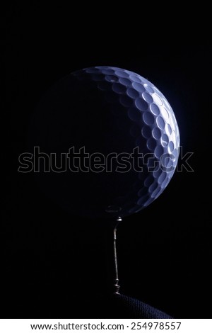 A golf ball on a tee, in dramatic black and white