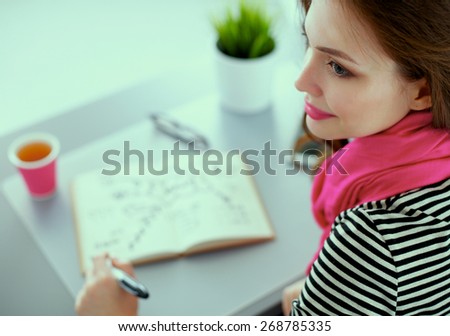 Young woman writes to diary on a white table