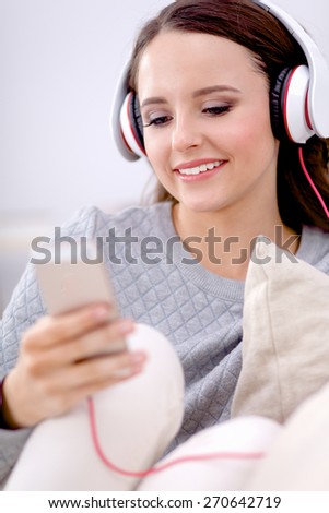 Young beautiful woman at home sitting on sofa and listening music