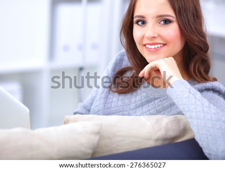 Happy pretty woman using laptop sitting on  sofa