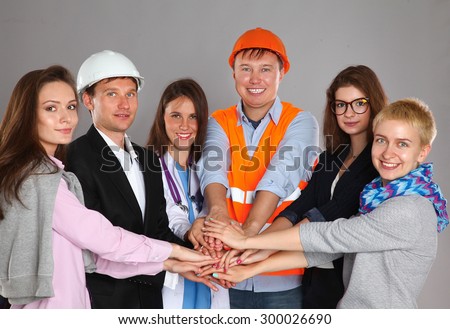 Portrait of smiling people with various occupations putting their hands on top of each other