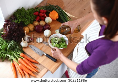 Young woman mixing fresh salad ,oil recharge