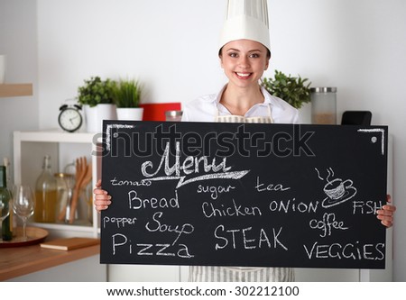 Chef woman holding the menu board , standing in kitchen