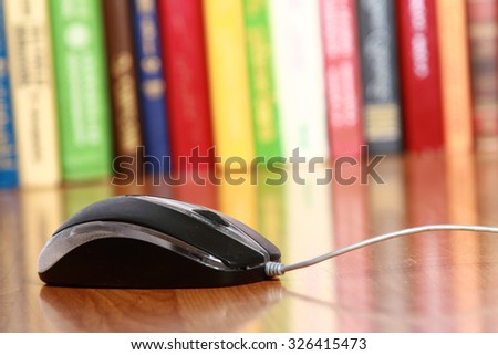 A computer mouse against books on the desk
