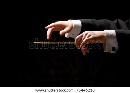 Concert conductor hands with a baton isolated on a black background