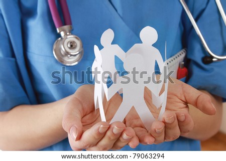A female doctor holding paper people, focus on the hand
