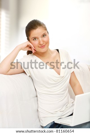 A woman works with a laptop on sofa indoors