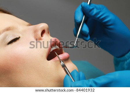 Close-up mouth examination by dentist. Isolated on grey