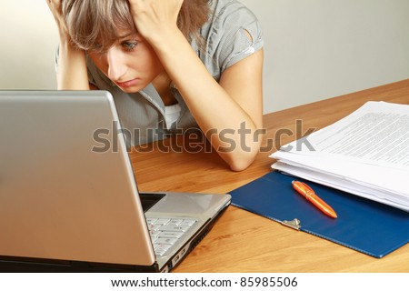 Portrait of a tired young businesswoman in front of a laptop, blueprint