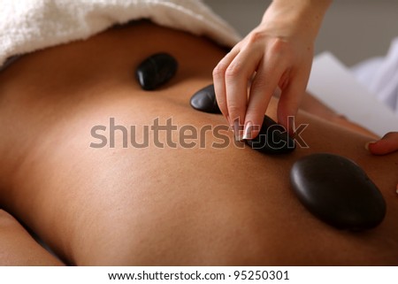 Bright young woman enjoying a back massage with hot stone in a spa