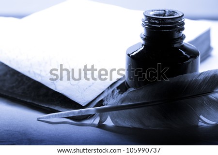 Old book with feather and inkpot in blue