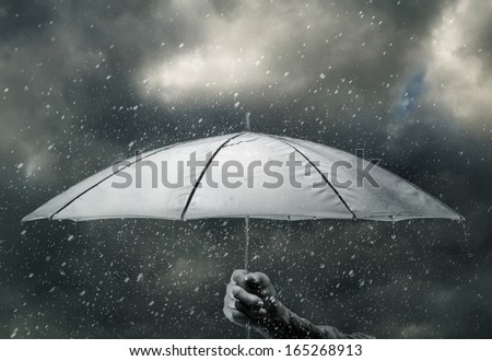 Umbrella in hand under raindrops of thunderstorm