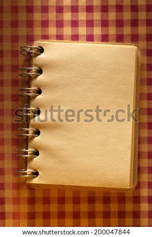 Blank open notepad on checked paper