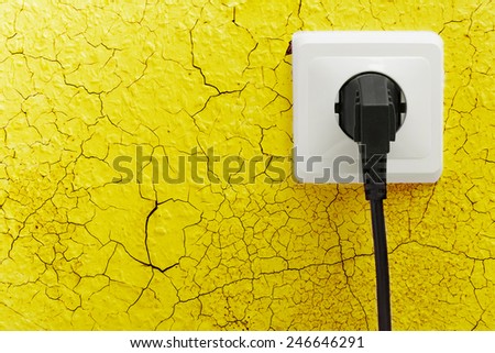 Wall plug socket on cracked colored wall background
