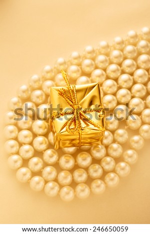 Present box on white pearl necklace in romantic light