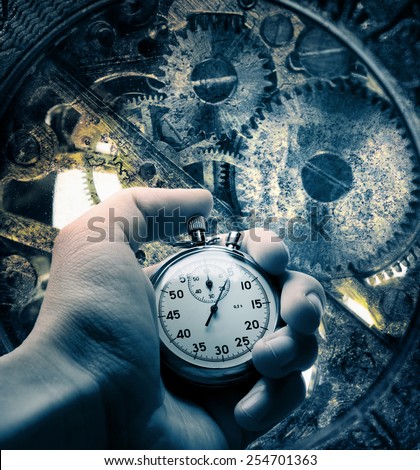 Old rusty clockwork inside mechanism and hand with stopwatch