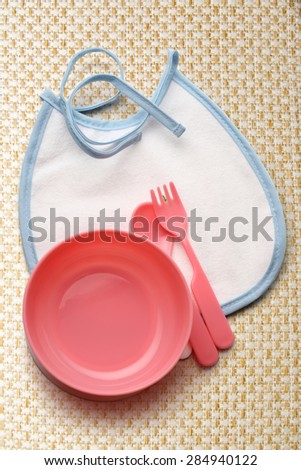 Bibs, bowl and spoon for baby in closeup