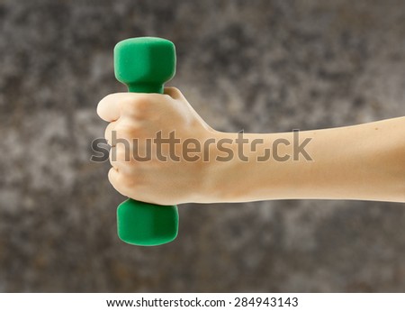 Female hand holding green dumbbell in closeup